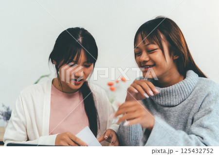 Female higher education student using laptop and studying book in home, Online learning. Female higher education student using laptop and studying book in home, Online learning. 125432752