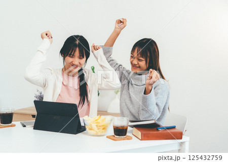 Female higher education student using laptop and studying book in home, Online learning. 125432759