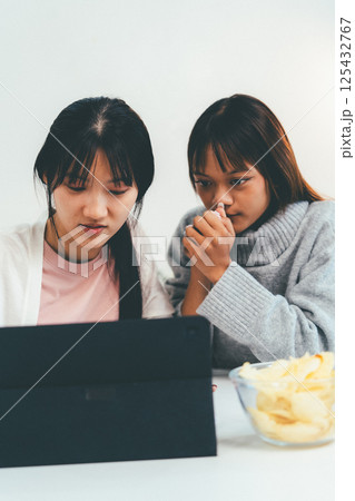 Female higher education student using laptop and studying book in home, Online learning. Female higher education student using laptop and studying book in home, Online learning. 125432767