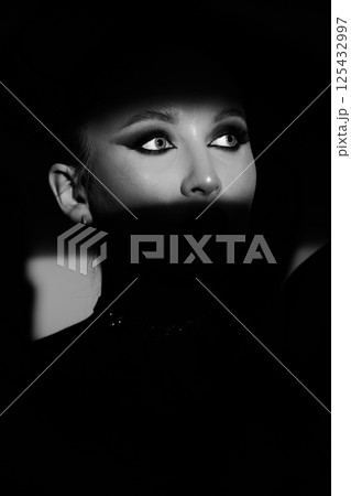 Woman portrait partly face covered with shadow and illuminated by studio light 125432997