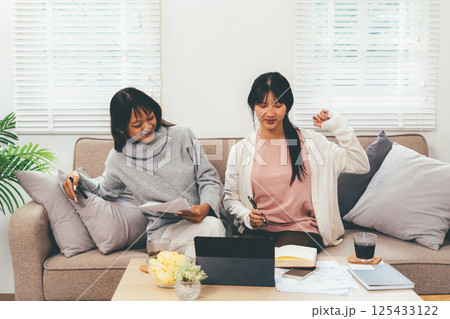 Female higher education student using laptop and studying book in home, Online learning. Female higher education student using laptop and studying book in home, Online learning. 125433122