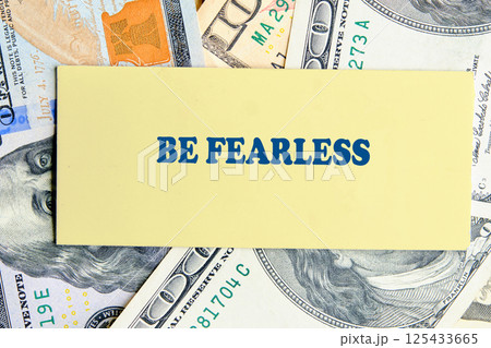 A bold statement urging individuals to embrace fearlessness can be seen prominently placed among various denominations of cash, symbolizing success and ambition 125433665