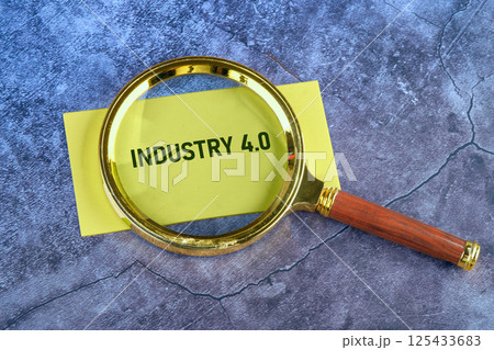 A magnifying glass is focused on a yellow note that reads Industry 4.0, set against a textured gray background, symbolizing innovation and technological advancement A magnifying glass is focused on a yellow note that reads Industry 4.0, set against a textured gray background, symbolizing innovation and technological advancement 125433683