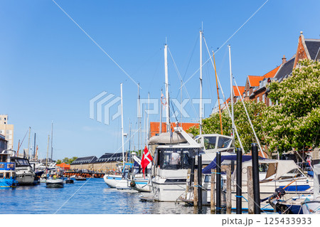Scenic view Christianshavn Copenhagen canal marina embankment with many boats vessel yachts moored against green trees and blue sky on sunny day. Christianshavn harbor neighborhood district cityscape 125433933