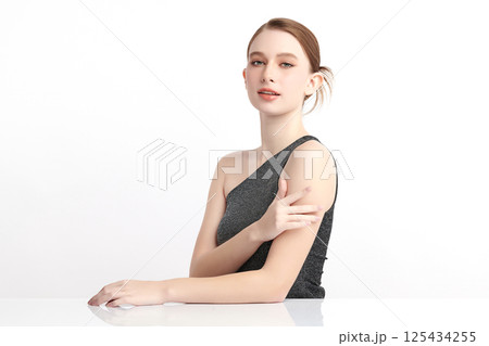 A beautiful young woman with clean, fresh skin against a white background. Skincare, facial treatment, cosmetology, beauty, and spa. An elegant portrait of an woman. 125434255