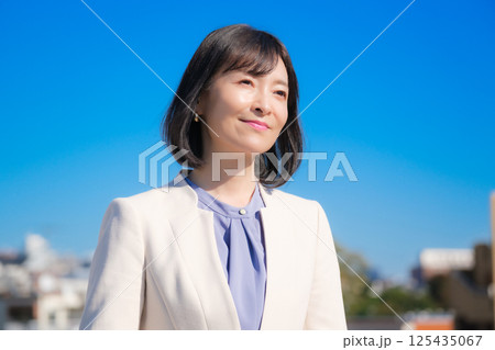 青空の下白いスーツ姿で自信あふれるミドルキャリアウーマン 青空の下白いスーツ姿で自信あふれるミドルキャリアウーマン 125435067