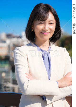 青空の下白いスーツ姿で自信あふれるミドルキャリアウーマン 青空の下白いスーツ姿で自信あふれるミドルキャリアウーマン 125435091