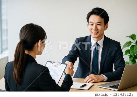 面接で握手する若手応募者と人事担当者・採用シーン 125435125