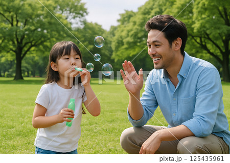 公園でシャボン玉遊びを楽しむ父娘・週末ファミリータイム 125435961