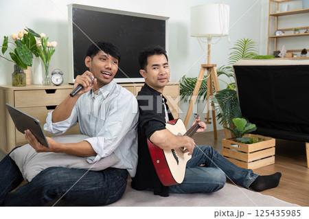 LGBT Friendship and Music. Two men enjoying a musical moment together, sharing laughter and creativity in a cozy living room. LGBT Friendship and Music. Two men enjoying a musical moment together, sharing laughter and creativity in a cozy living room. 125435985