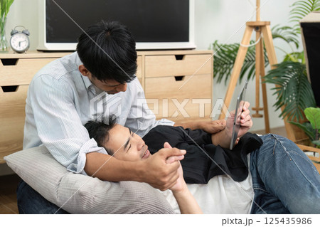 LGBTQ Love and Comfort. Two men sharing a tender moment while watching a tablet together. 125435986