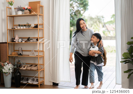 Family Bonding and School Journey. A mother and son walking together after packing for school. 125436005