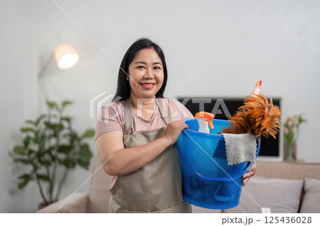 Cleaning and Home Maintenance. A woman smiling while holding a bucket of cleaning supplies. Cleaning and Home Maintenance. A woman smiling while holding a bucket of cleaning supplies. 125436028