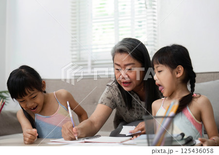 Back to School and Learning Together. A grandmother guides her granddaughters in a drawing activity. Back to School and Learning Together. A grandmother guides her granddaughters in a drawing activity. 125436058