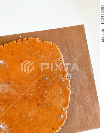 Gingerbread dough rolling on brown baking mat with flour dusting 125436399