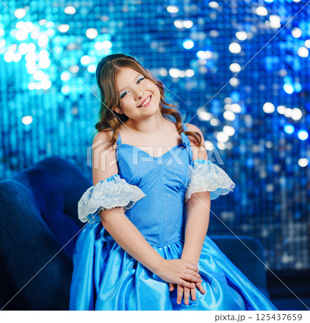 Cute teenage girl in blue doll dress posing against sequin wall background Cute teenage girl in blue doll dress posing against sequin wall background 125437659