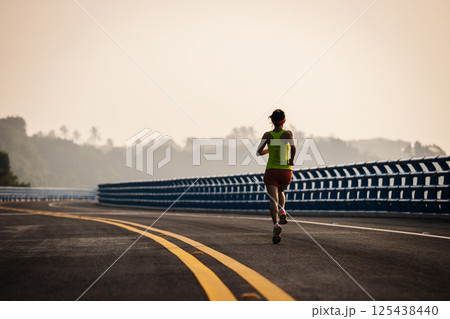 Asian fitness woman runner running on seaside bridge 125438440