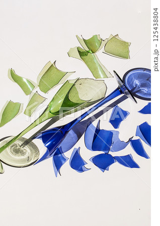 Broken Green and Blue Wine Glasses, Fragments Surrounding Them on White Background with Reflections and Harsh Shadow. 125438804
