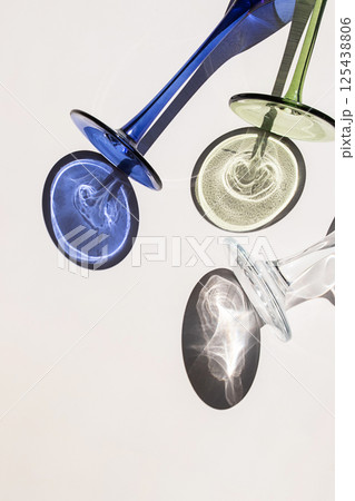 Three Wine Glasses Lying on White Surface with Colorful Shadows and Sun Glare Visible. Three Wine Glasses Lying on White Surface with Colorful Shadows and Sun Glare Visible. 125438806