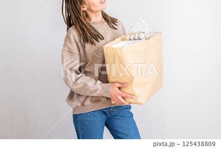 Woman with Dreadlocks Holding Paper Bag with Plastic Packing for Recycling. Environmental Concept for Earth Day. Woman with Dreadlocks Holding Paper Bag with Plastic Packing for Recycling. Environmental Concept for Earth Day. 125438809