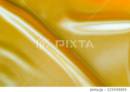 Top view of golden yellow silk with soft curves and vibrant reflective surface. Suitable for design and wallpaper background 125438893