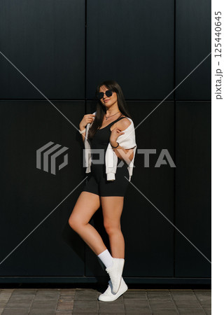Stylish Woman Posing Against Black Wall 125440645