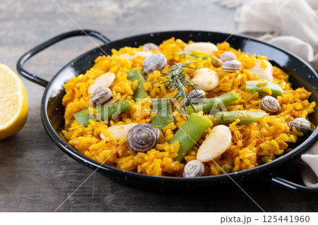 Traditional Valencian paella with rabbit, chicken, garrofon beans, snails, Moroccan green beans and saffron on wooden table Traditional Valencian paella with rabbit, chicken, garrofon beans, snails, Moroccan green beans and saffron on wooden table 125441960