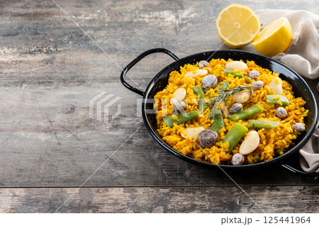 Traditional Valencian paella with rabbit, chicken, garrofon beans, snails, Moroccan green beans and saffron on wooden table 125441964