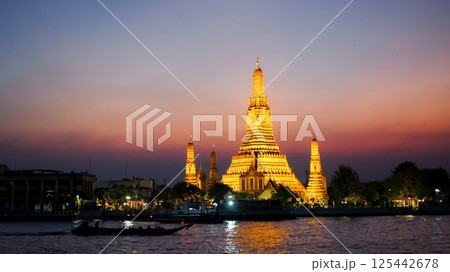 Scenic twilight view of Wat Arun illuminated against a vivid sunset sky, with reflections on the Chao Phraya River. Perfect for travel, culture, and destination themes. Scenic twilight view of Wat Arun illuminated against a vivid sunset sky, with reflections on the Chao Phraya River. Perfect for travel, culture, and destination themes. 125442678
