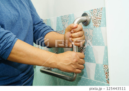 Asian woman patient use toilet support rail in bathroom, handrail safety grab bar, security in nursing hospital. 125443511