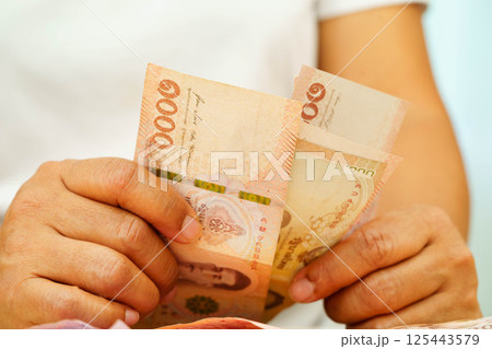 Asian woman counting Thai baht banknote money and holding in hand, investment economy, accounting business and banking. Asian woman counting Thai baht banknote money and holding in hand, investment economy, accounting business and banking. 125443579