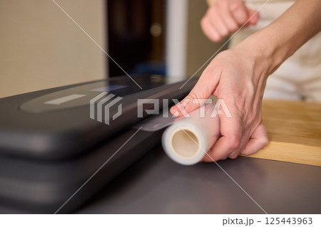 Hands Skillfully Preparing Vacuum Sealing for Food Preservation and Storage Purposes 125443963