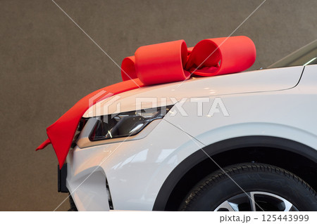 The new car is wrapped in a red bow. Beautiful gift concept. 125443999
