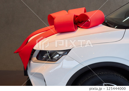 The new car is wrapped in a red bow. Beautiful gift concept. 125444000