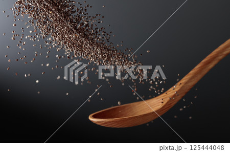 Chia seeds in motion on a dark background. Chia seeds in motion on a dark background. 125444048