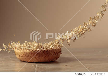 Oat flakes in motion on a beige background. Oat flakes in motion on a beige background. 125444056