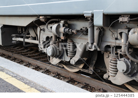Detailed view of train undercarriage showcasing suspension system and wheel assembly at a railway station 125444385
