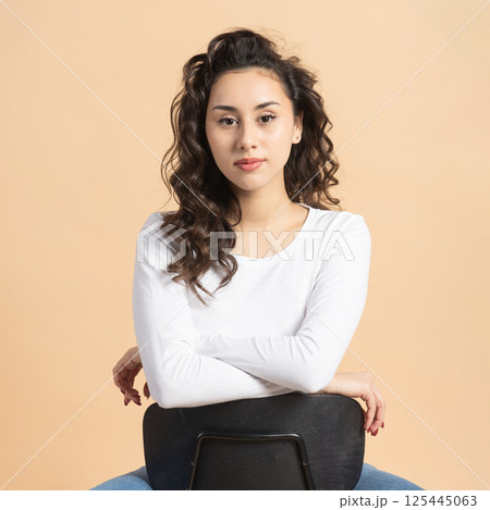 Studio portrait of woman sitting on chair Studio portrait of woman sitting on chair 125445063