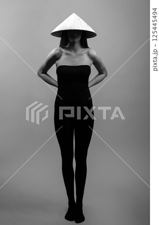 Slim woman wearing cone-shaped Asian cane hat Slim woman wearing cone-shaped Asian cane hat 125445494