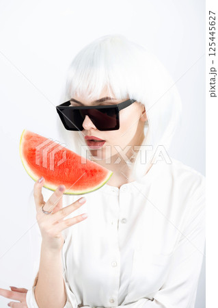Woman with white wig holding slice of red watermelon 125445627