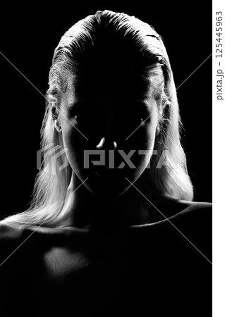 Studio portrait of woman silhouette partly illuminated with light 125445963