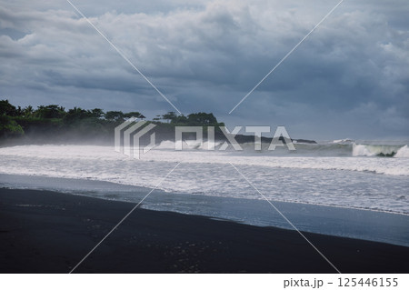 Volcanic black sandy beach with ocean waves in Bali. Beach and dark sky Volcanic black sandy beach with ocean waves in Bali. Beach and dark sky 125446155