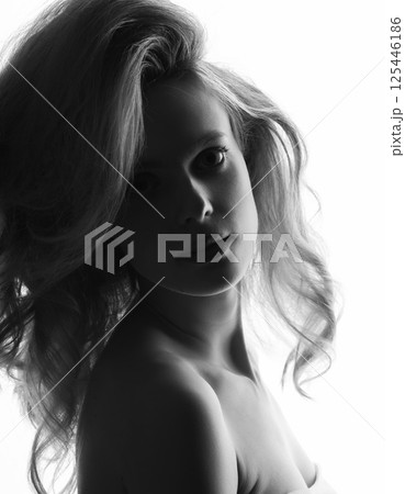 Beautiful woman with big wavy hair studio portrait in bright background Beautiful woman with big wavy hair studio portrait in bright background 125446186