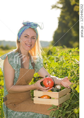 Portrait of beautiful woman picking up vegetables in garden 125446202