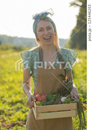 Portrait of beautiful woman picking up vegetables in garden 125446203