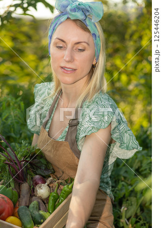 Portrait of beautiful woman picking up vegetables in garden Portrait of beautiful woman picking up vegetables in garden 125446204