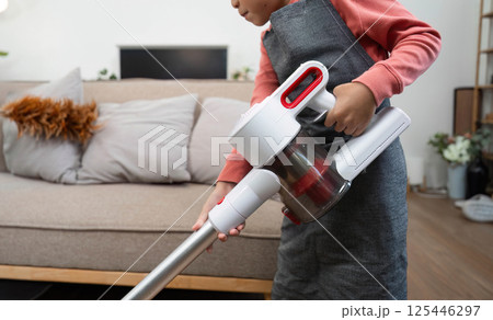 Child Learning and Cleaning. A child vacuuming the living room with a handheld vacuum. 125446297
