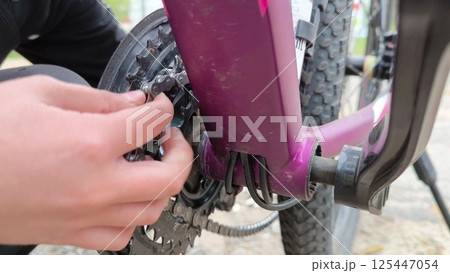 Bicycle breakdown. A boy repairs a bicycle chain outdoors. Work by hand. using a bicycle chain. Bicycle breakdown. A boy repairs a bicycle chain outdoors. Work by hand. using a bicycle chain. 125447054