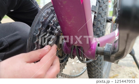 Bicycle breakdown. A boy repairs a bicycle chain outdoors. Work by hand. using a bicycle chain. Bicycle breakdown. A boy repairs a bicycle chain outdoors. Work by hand. using a bicycle chain. 125447055