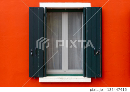 Green shutters on vivid red wall 125447416